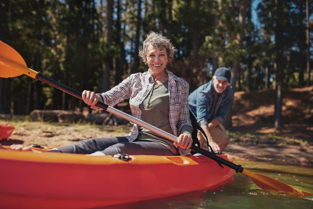Portrait of happy senior woman in a kayak holding paddles. 